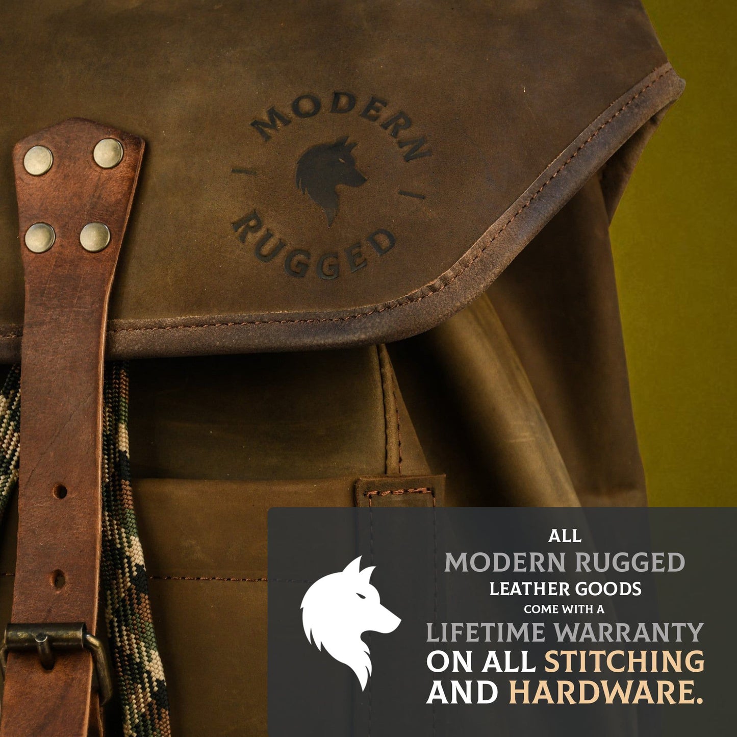 Close-up of brown bovine leather satchel bag with "Modern Rugged" logo and warranty text on dark overlay.