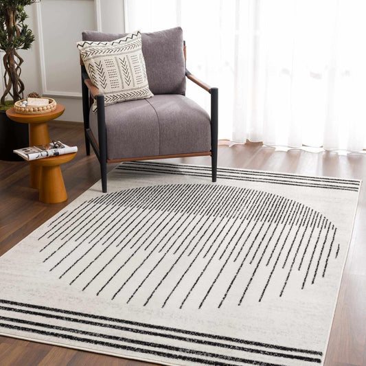 Angus abstract black and white area rug with southwestern stripes in a modern living room setting with a gray chair.