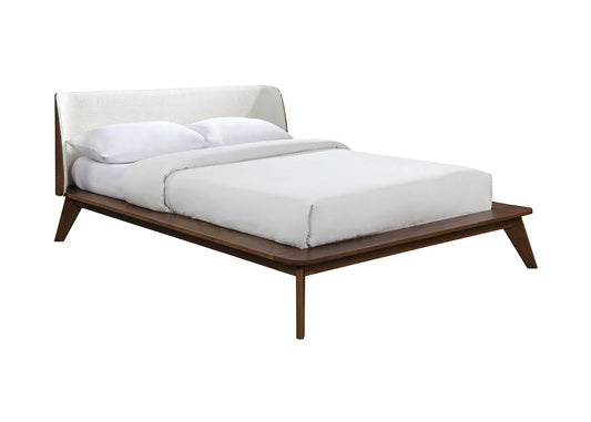A walnut mid century bed frame showcasing a low-profile platform structure and a light textured fabric panel headboard on a solid background