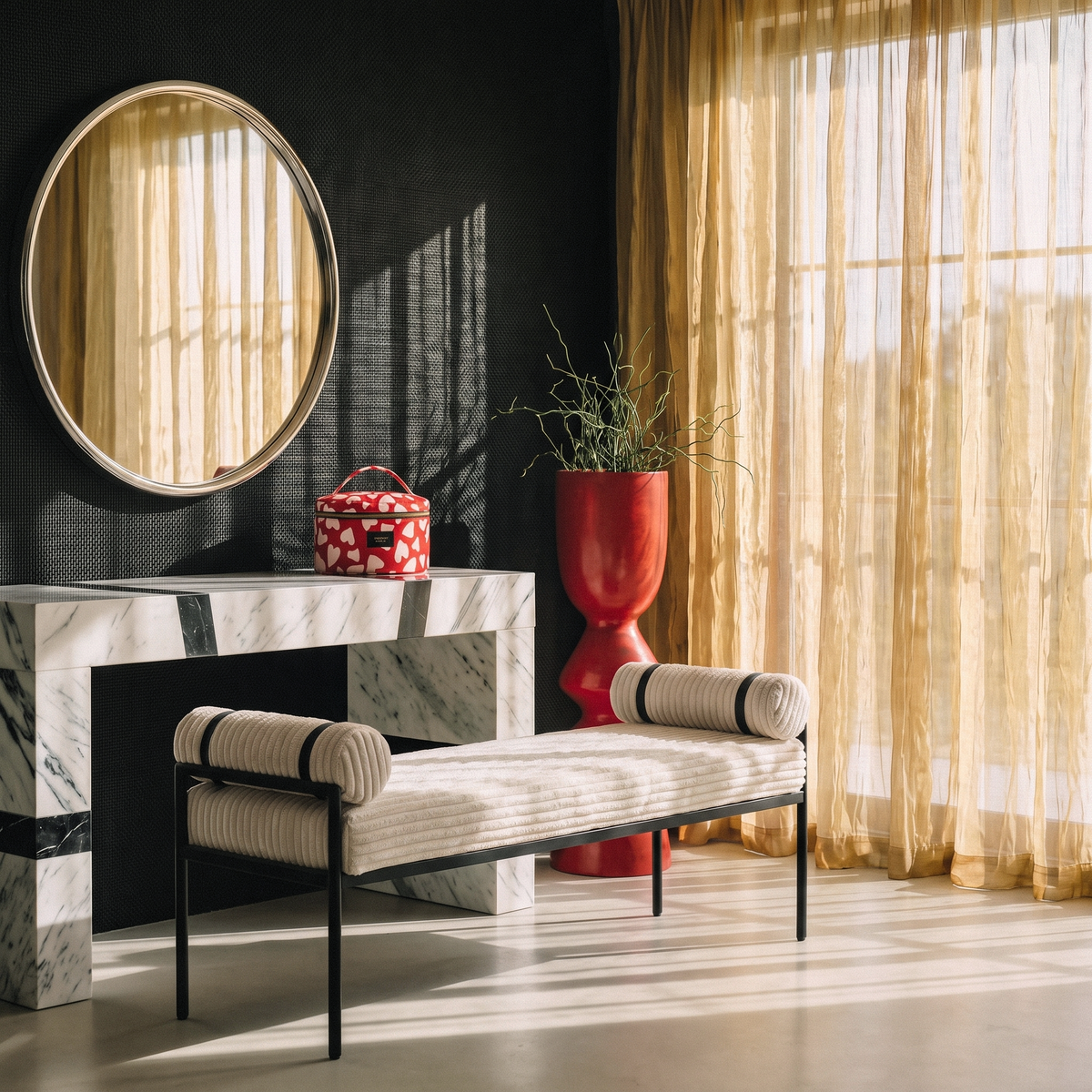 Handcrafted toiletry and cosmetic bag styled on marble console with upholstered bench round mirror and sheer gold curtains in luxury interior