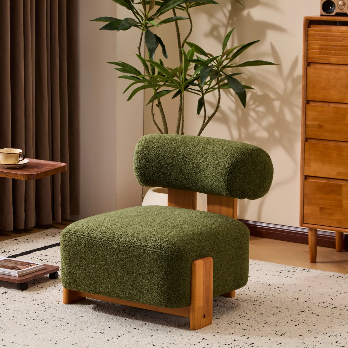 Modern green upholstered lounge chair with wooden legs in stylish living room with plant and wooden dresser