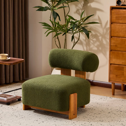 Modern green upholstered lounge chair with wooden legs in stylish living room with plant and wooden dresser