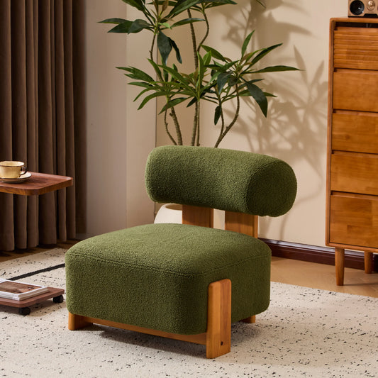 Modern green upholstered lounge chair with wooden legs in stylish living room with plant and wooden dresser