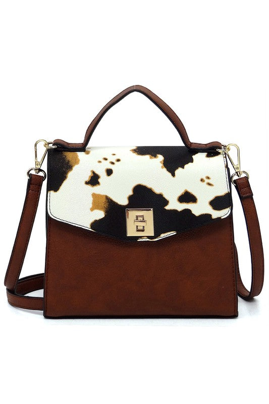 Brown leather handbag with cow print flap and gold clasp, featuring top handle and detachable shoulder strap