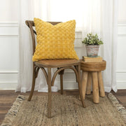 Yellow textured pillow on wooden chair, rustic stool with potted plant and books, cozy decor