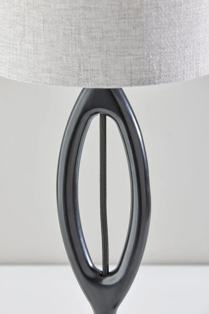 Close-up of the sculpted oval silhouette of the black wood table lamp featuring a smooth charcoal finish and visible cord detail.