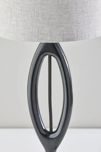 Close-up of the sculpted oval silhouette of the black wood table lamp featuring a smooth charcoal finish and visible cord detail.