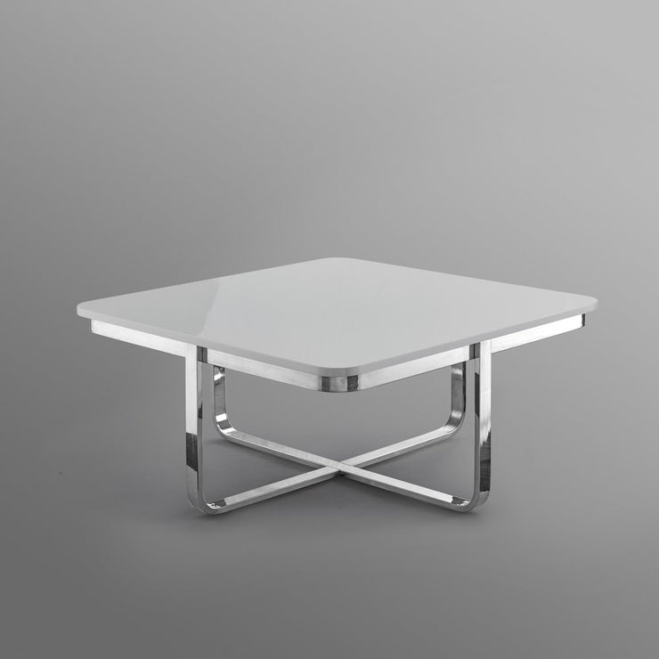 Modern square coffee table with glossy white top and chrome metal X-base on grey background