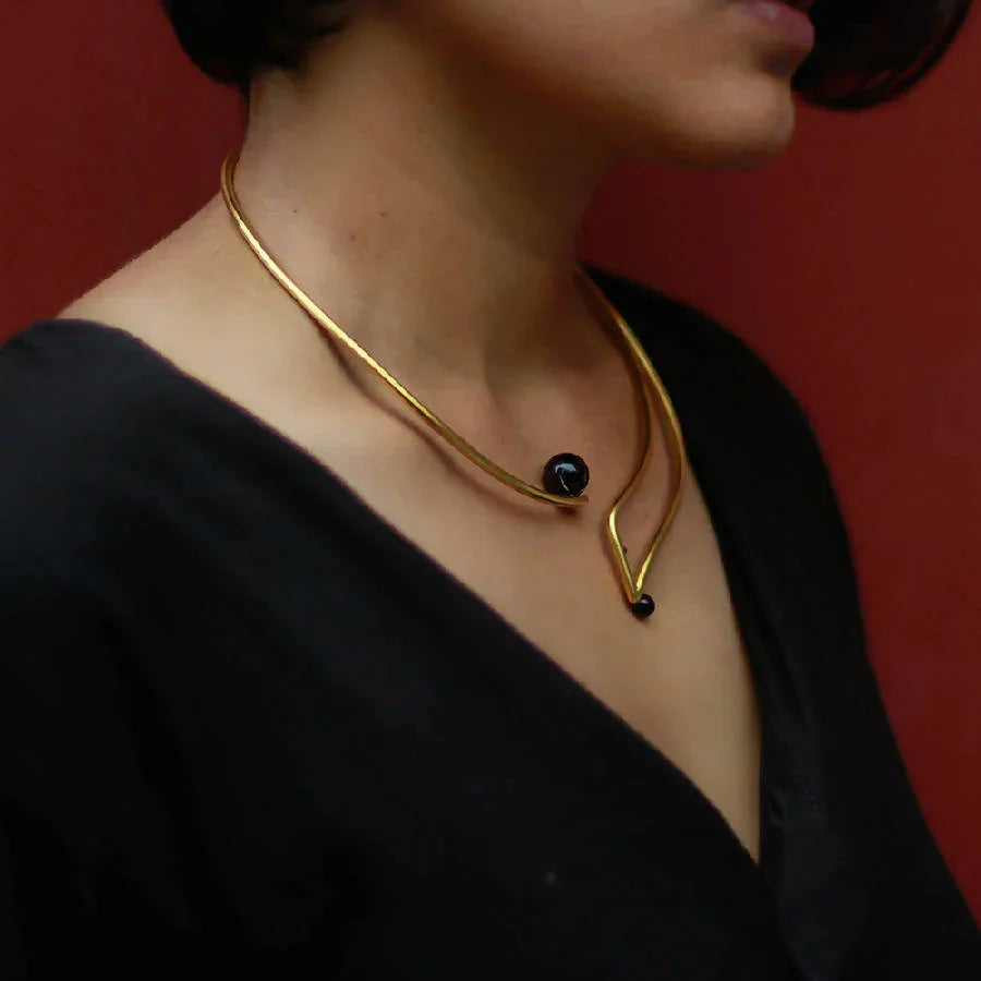 Swara Necklace by Dotto Objects featuring gold-washed brass curves and black stone beads.