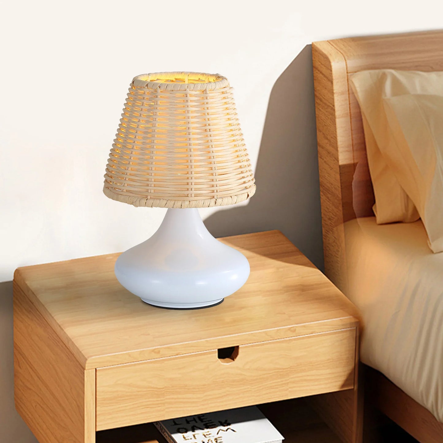 White modern table lamp with woven rattan shade on wooden bedside table in bedroom