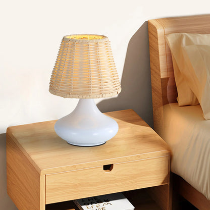 White modern table lamp with woven rattan shade on wooden bedside table in bedroom
