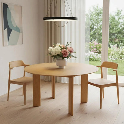 Modern dining room with round wood table, two chairs, floral centerpiece, and pendant light