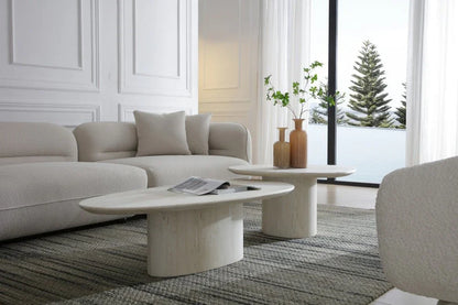 Lifestyle view of the Sia 51-inch beige genuine marble coffee table in a contemporary living room with a matching nesting table, bouclé sofa, and outdoor scenery.