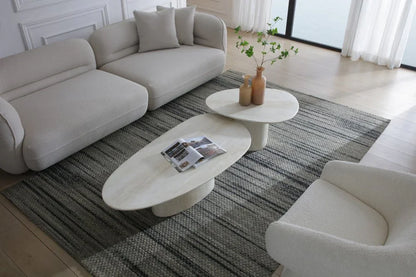 High-angle lifestyle view of the Sia 51-inch beige marble oval coffee table and nesting table on a textured area rug.