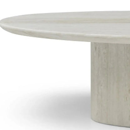 Detailed close-up of the Sia 51-inch beige marble coffee table showing the thick oval top resting on the matching stone pedestal base.