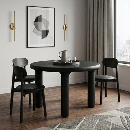Dining room with a black round table and chairs, abstract art on the wall, and large window.