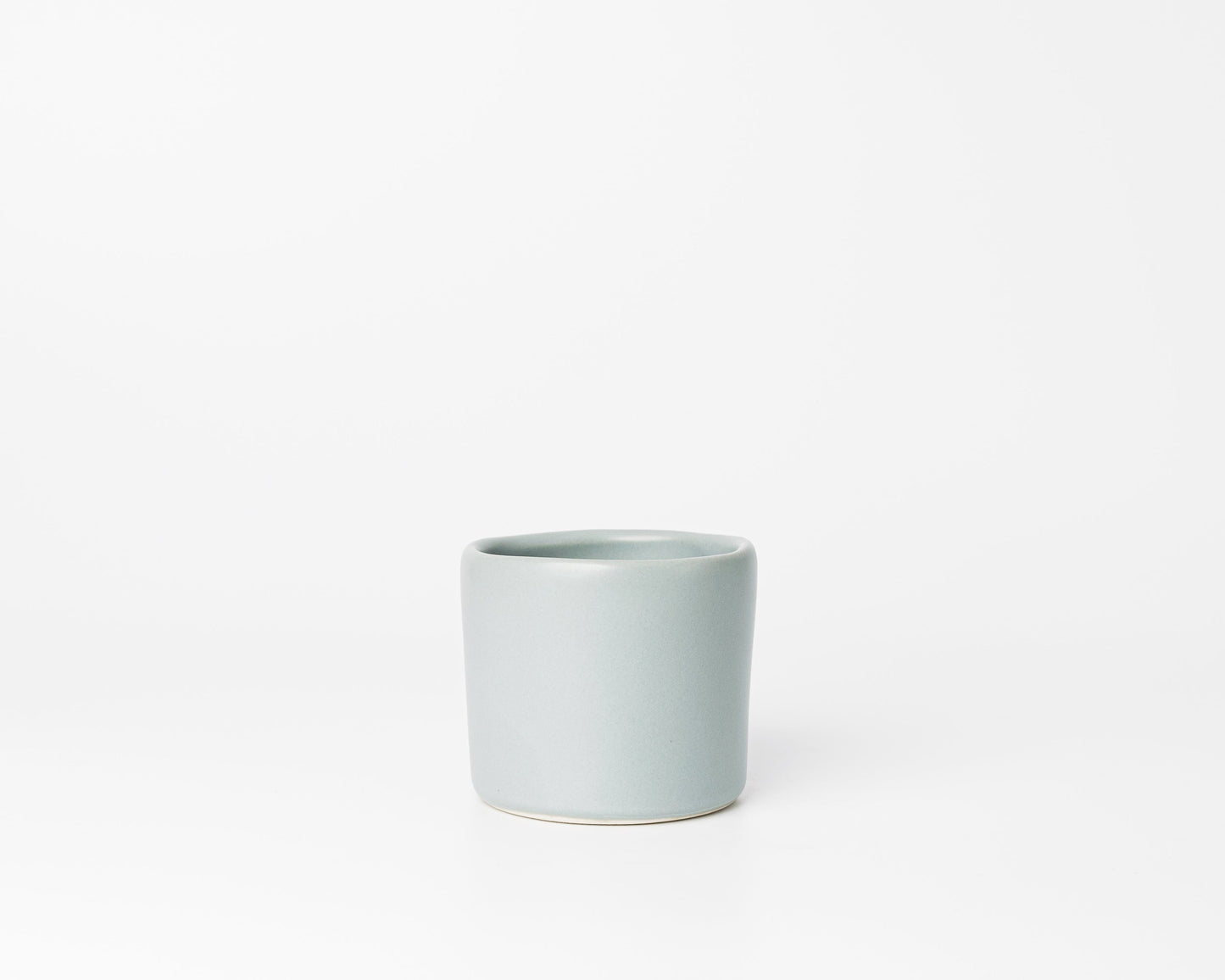 Minimalist light gray ceramic cup with slight uneven rim on white background