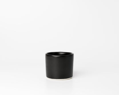 Minimalist black ceramic cup with smooth matte finish on white background