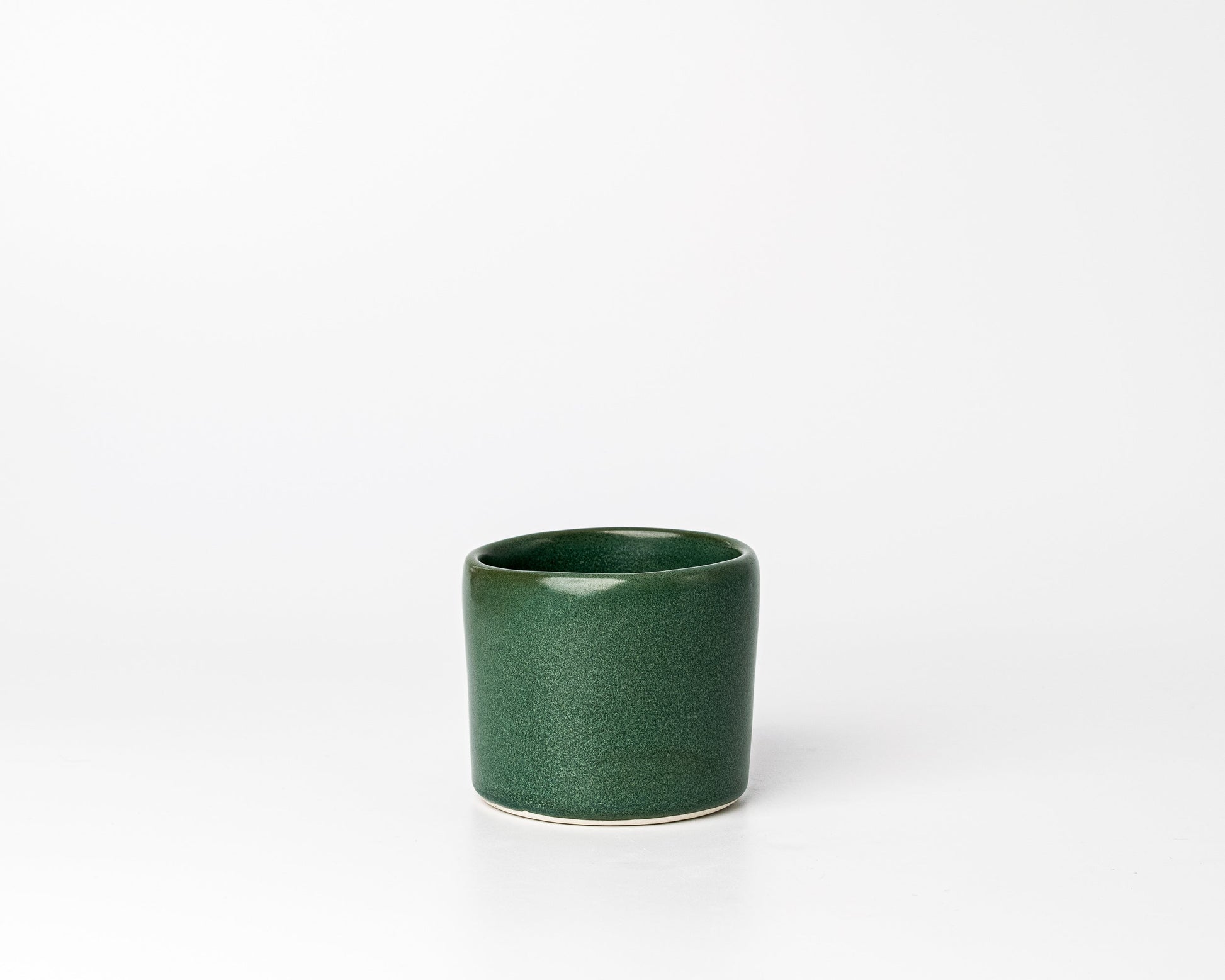 Minimalist green ceramic cup with smooth finish on white background