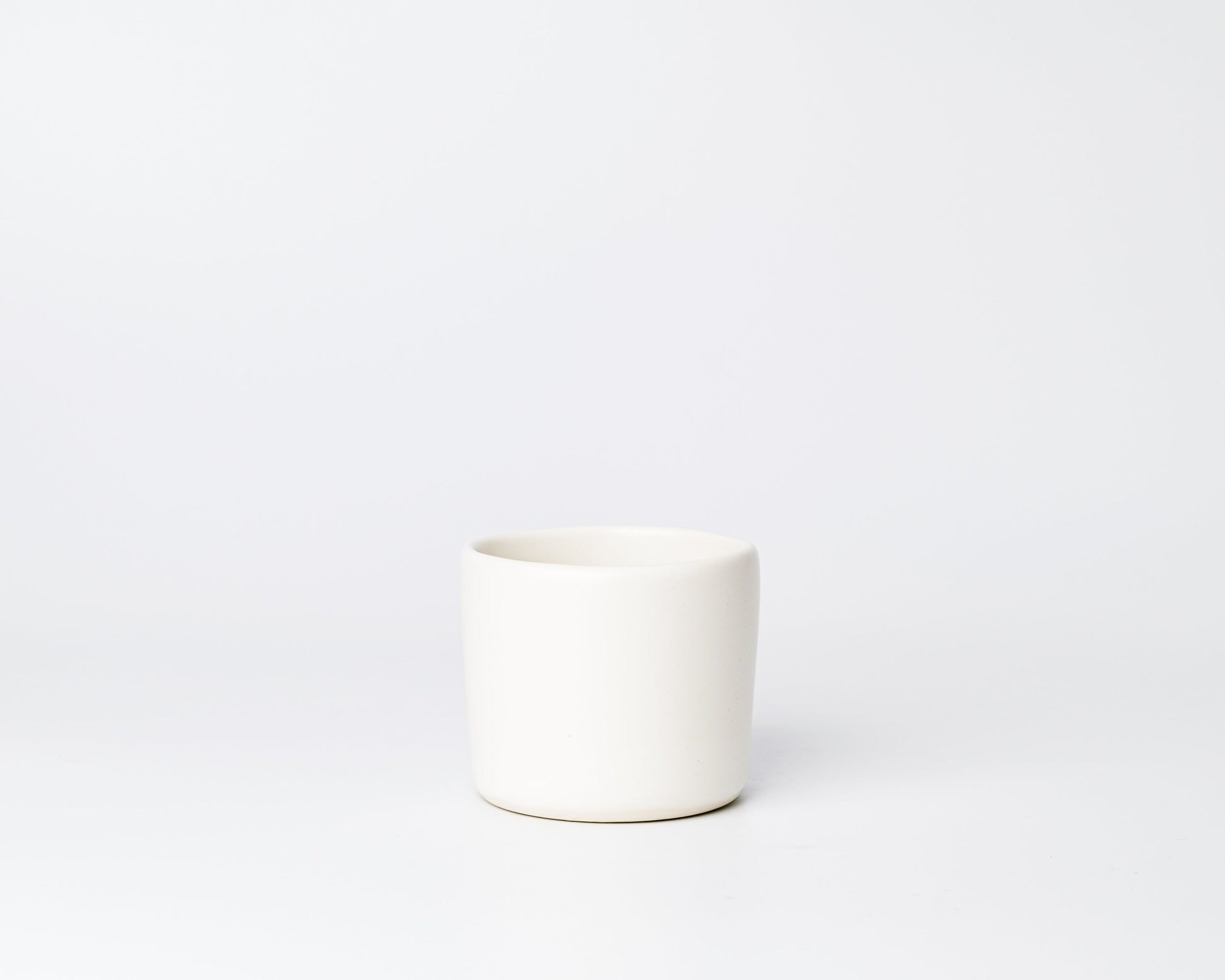 Minimalist white ceramic cup on plain white background