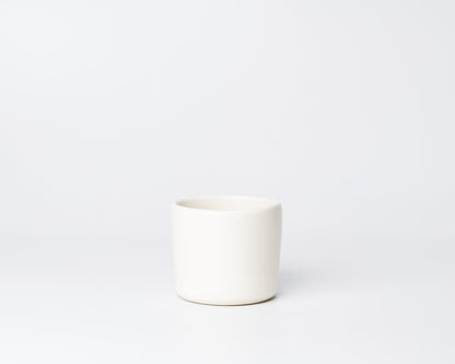 Minimalist white ceramic cup on plain white background
