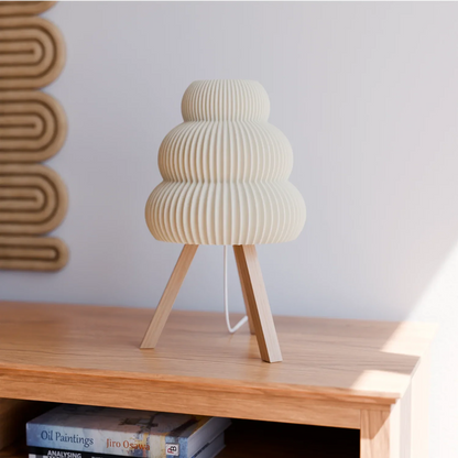 Modern beige ceramic table lamp with ribbed design and wooden tripod legs on wooden sideboard
