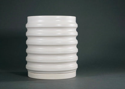 White ceramic vase with horizontal ridges on dark gray background