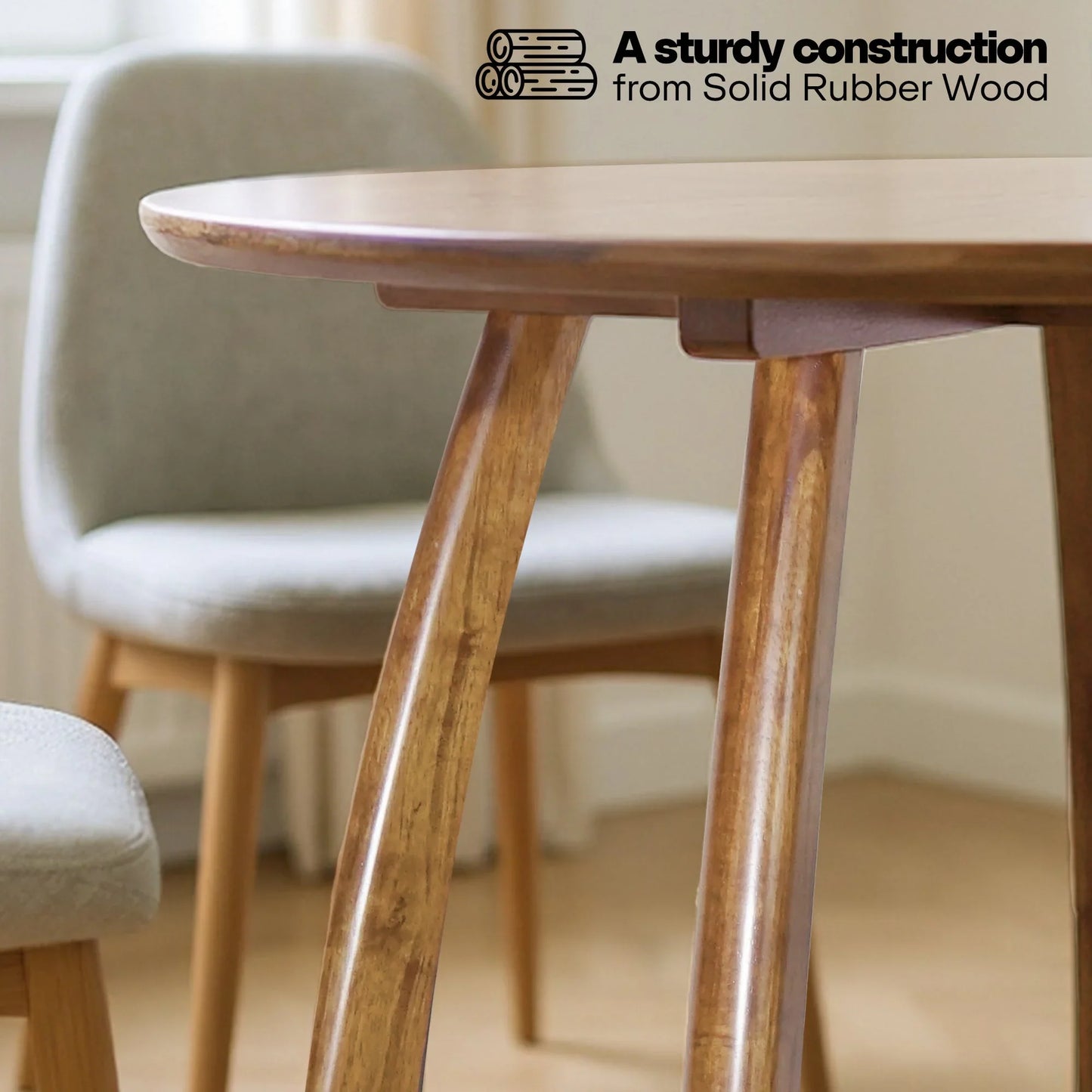 Close-up of solid rubber wood dining table legs with a modern grey upholstered chair in the background