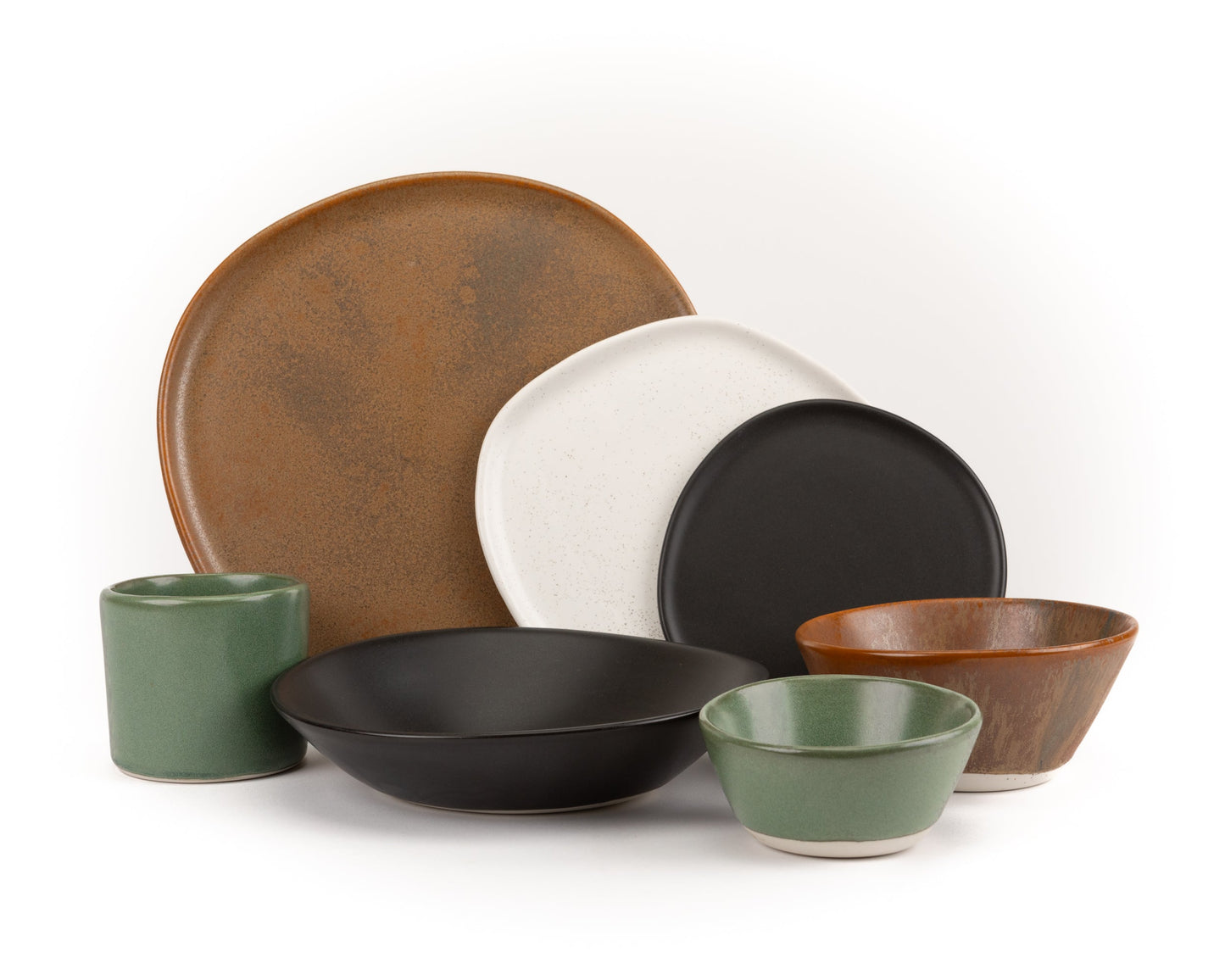 7-piece ceramic dinnerware set with matte brown, black, white, and green plates and bowls on white background