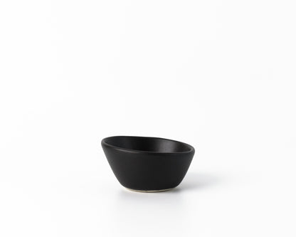 Small black ceramic dessert bowl with an organic, asymmetrical shape on white background