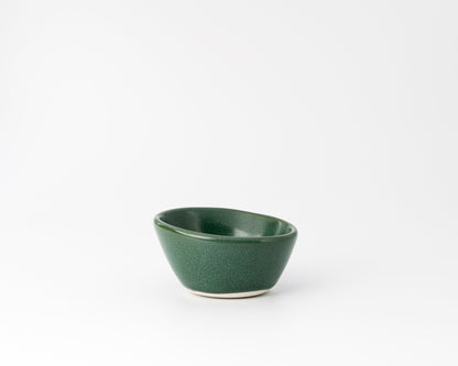 Handcrafted dark green ceramic dessert bowl with smooth asymmetric design on white background