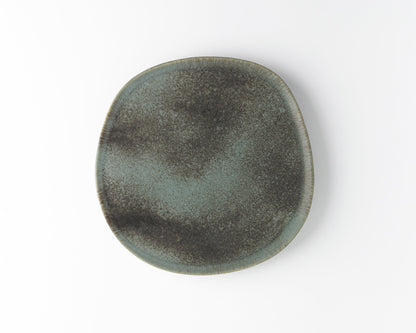Round ceramic dinner plate with speckled gray and black glaze on white background