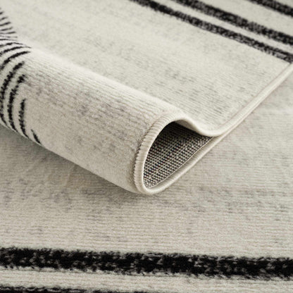 Close-up of Angus abstract black and white area rug showing rolled edge, texture, and non-slip backing