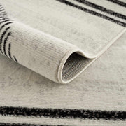 Close-up of Angus abstract black and white area rug showing rolled edge, texture, and non-slip backing