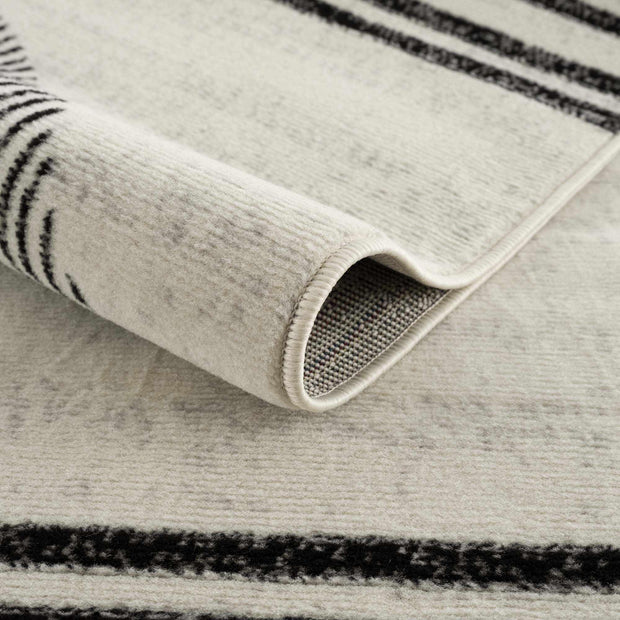 Close-up of Angus abstract black and white area rug showing rolled edge, texture, and non-slip backing
