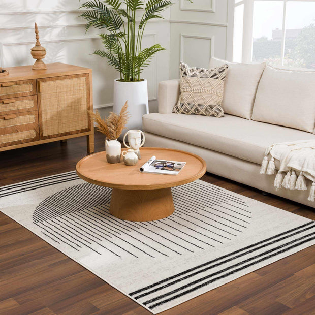 Angus Abstract Black and White Area Rug in a living room with a light couch and wooden furniture, southwestern flair.