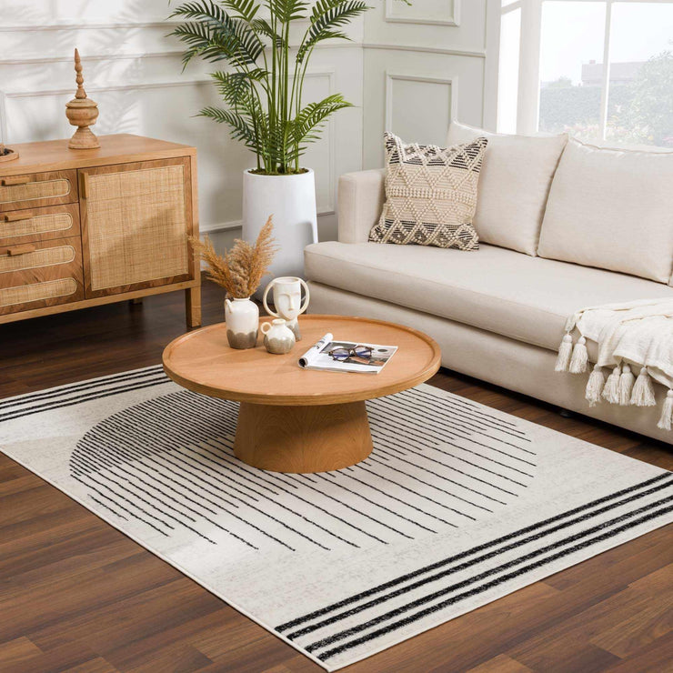 Angus Abstract Black and White Area Rug in a living room with a light couch and wooden furniture, southwestern flair.