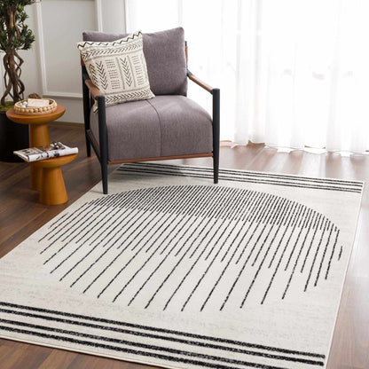 Angus abstract black and white area rug with southwestern stripes in a modern living room setting with a gray chair.