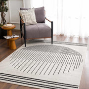 Angus abstract black and white area rug with southwestern stripes in a modern living room setting with a gray chair.
