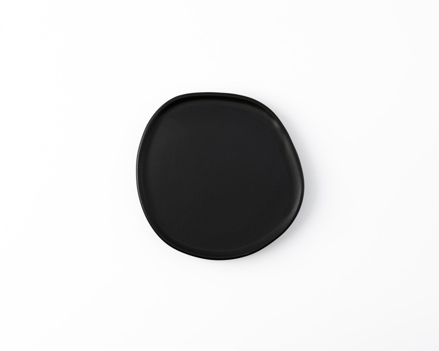 Minimalist black ceramic plate with irregular shape on white background