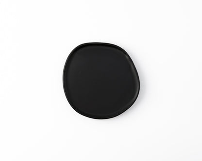 Minimalist black ceramic plate with irregular shape on white background