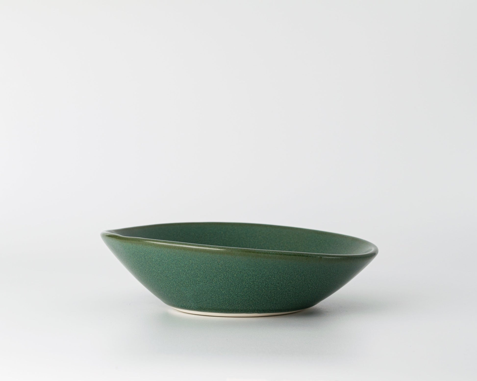 Green ceramic shallow soup bowl with a smooth matte finish on white background