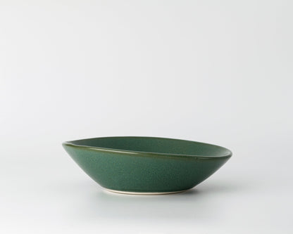 Green ceramic shallow soup bowl with a smooth matte finish on white background