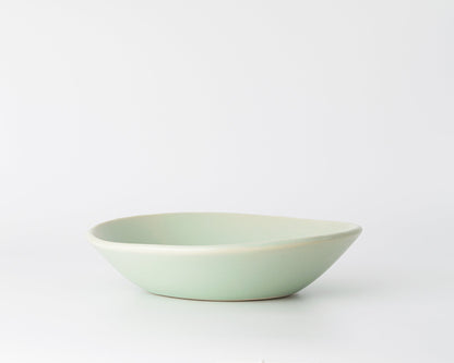 Light green ceramic soup bowl with a smooth, shallow design on white background
