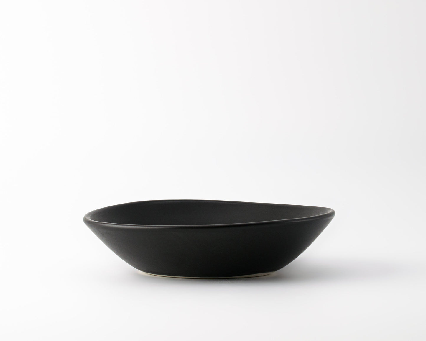Minimalist black ceramic soup bowl on white background, modern kitchenware