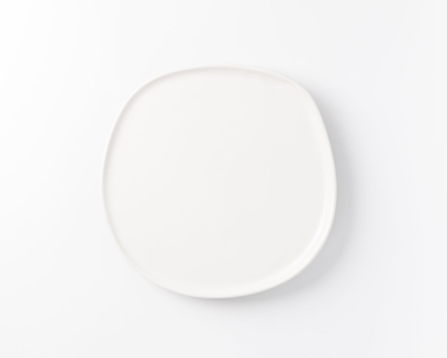 Simple white ceramic plate with rounded square shape on white background