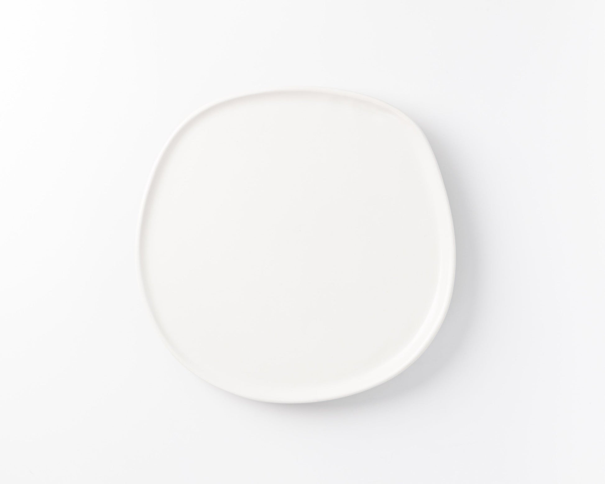 Simple white ceramic plate with rounded square shape on white background