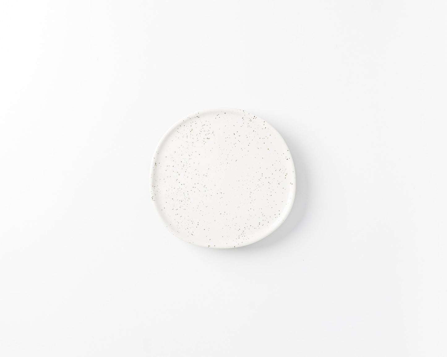 White ceramic plate with brown speckled pattern on a plain white background