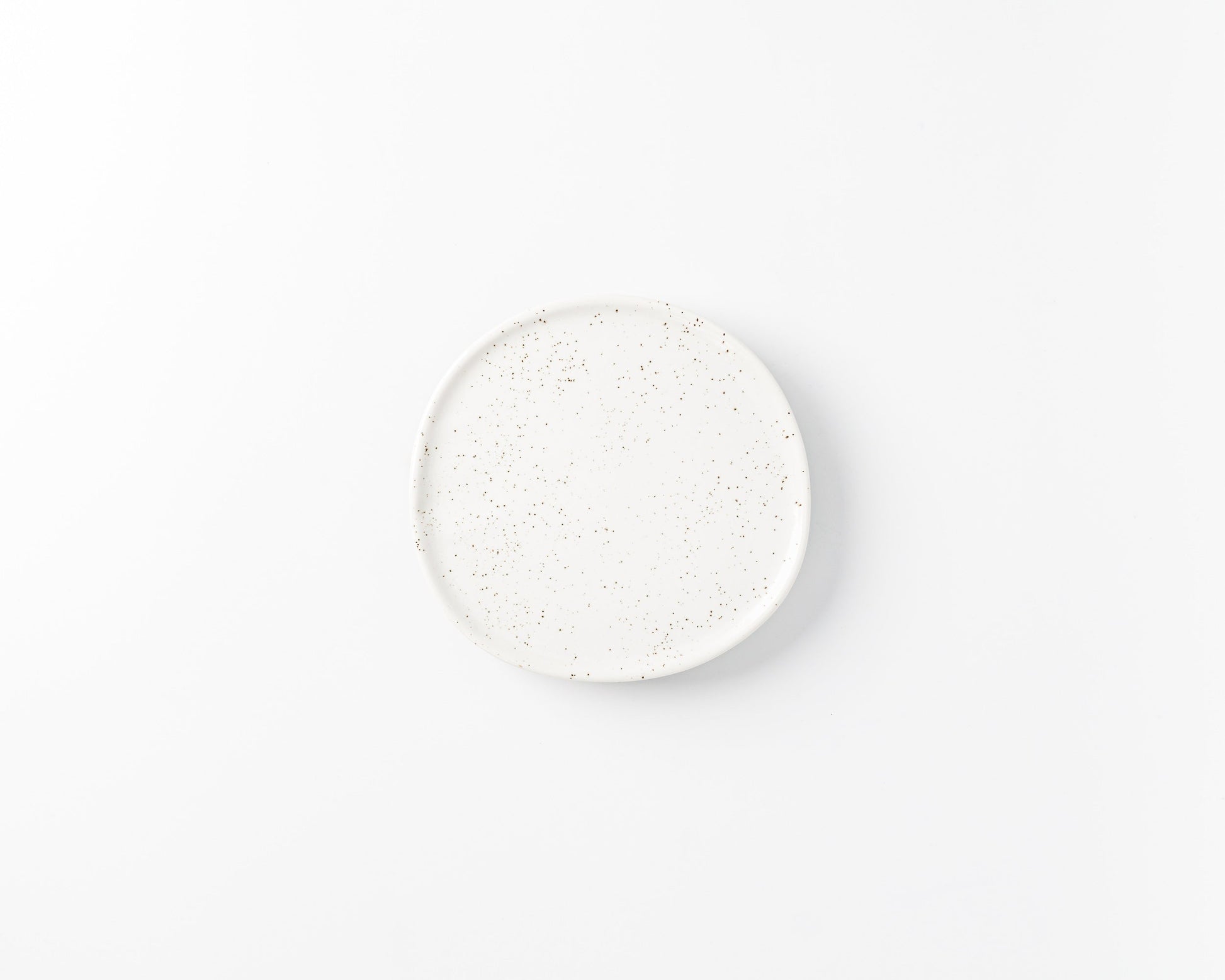 White ceramic plate with brown speckled pattern on a plain white background