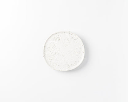 White ceramic plate with brown speckled pattern on a plain white background